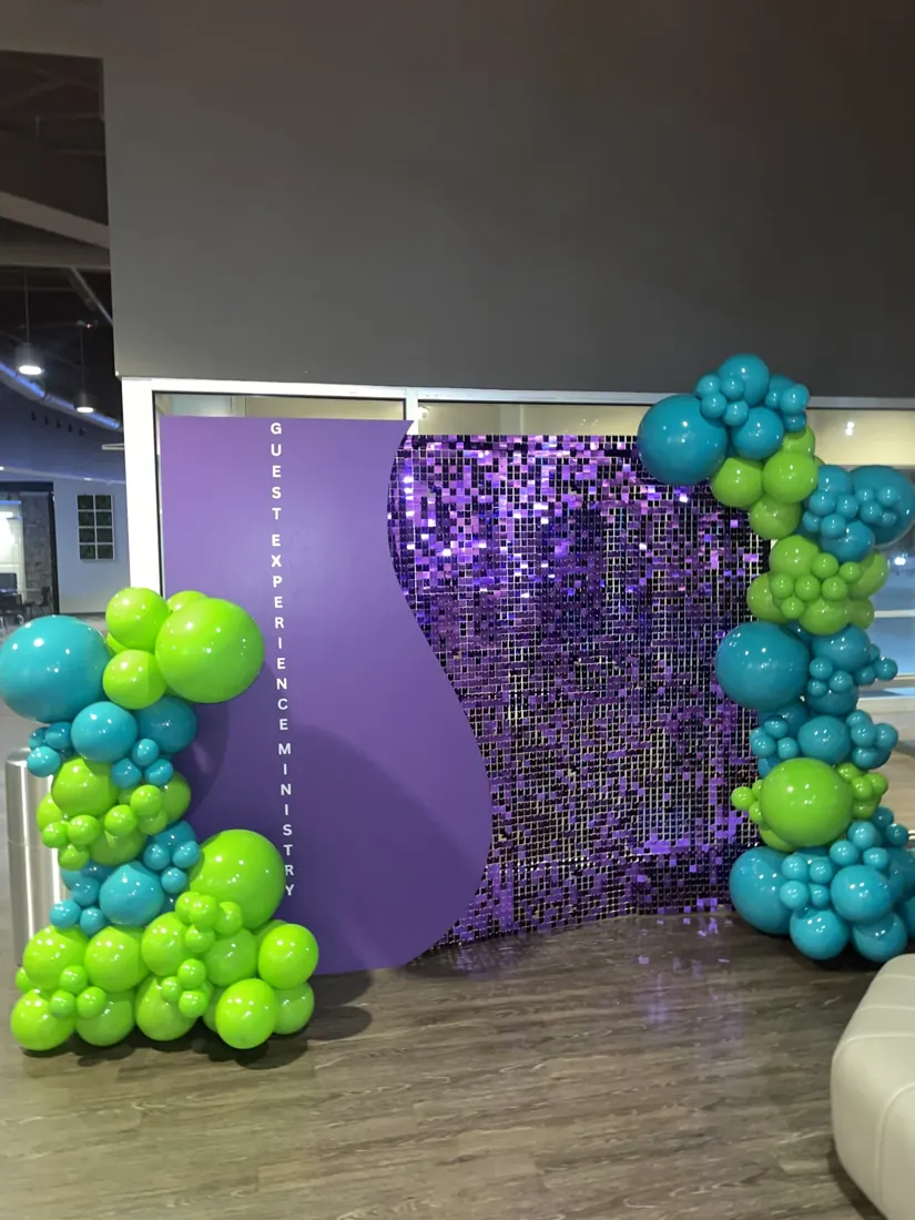 Turquoise and lime balloon clusters beside a purple sequin backdrop