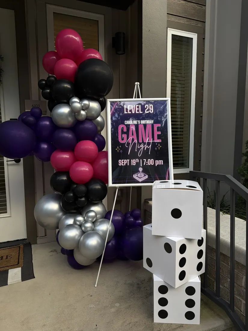 Purple, pink, black and silver balloons with oversized dice at a game night display — detail view